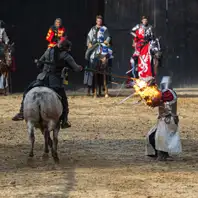 Ritterspiele auf Burg Satzvey. Ein Reiter sticht mit Lanze auf Ritter mit Schild. Das Schild fängt Feuer